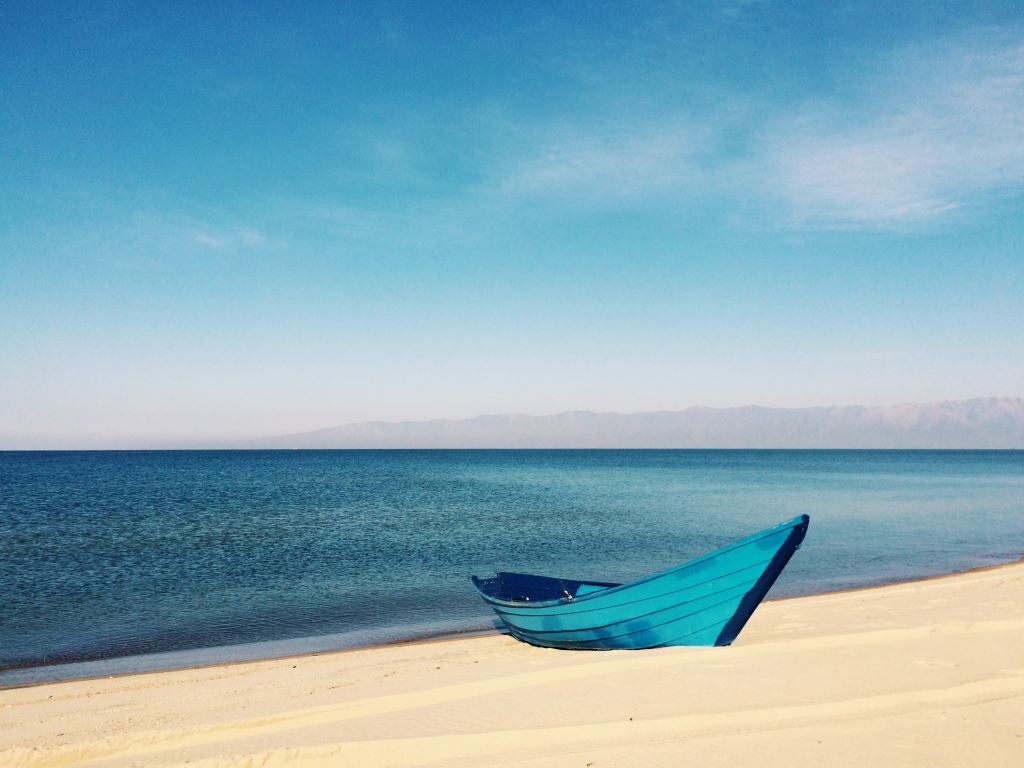blue-boat-near-ocean-on-sand